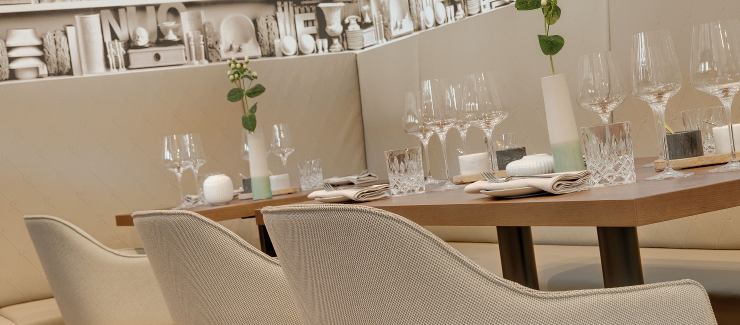 Gedeckte Tische mit modernen, grau bezogenen Sitzmöbeln