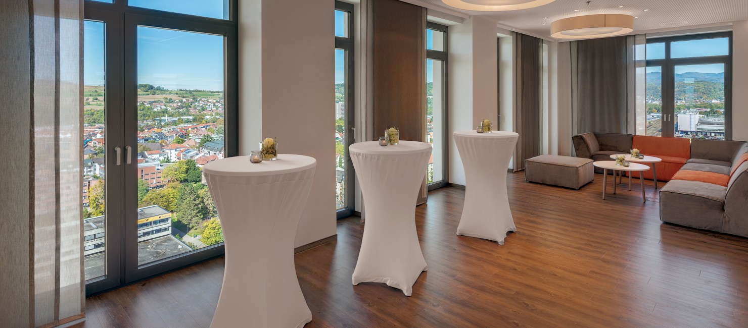 Weiß bezogene Stehtische und Sitzecke im Tagungsbereich des Hotel Stadt Lörrach